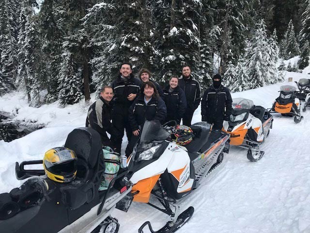 Family outdoors with snowmobiles on the trail